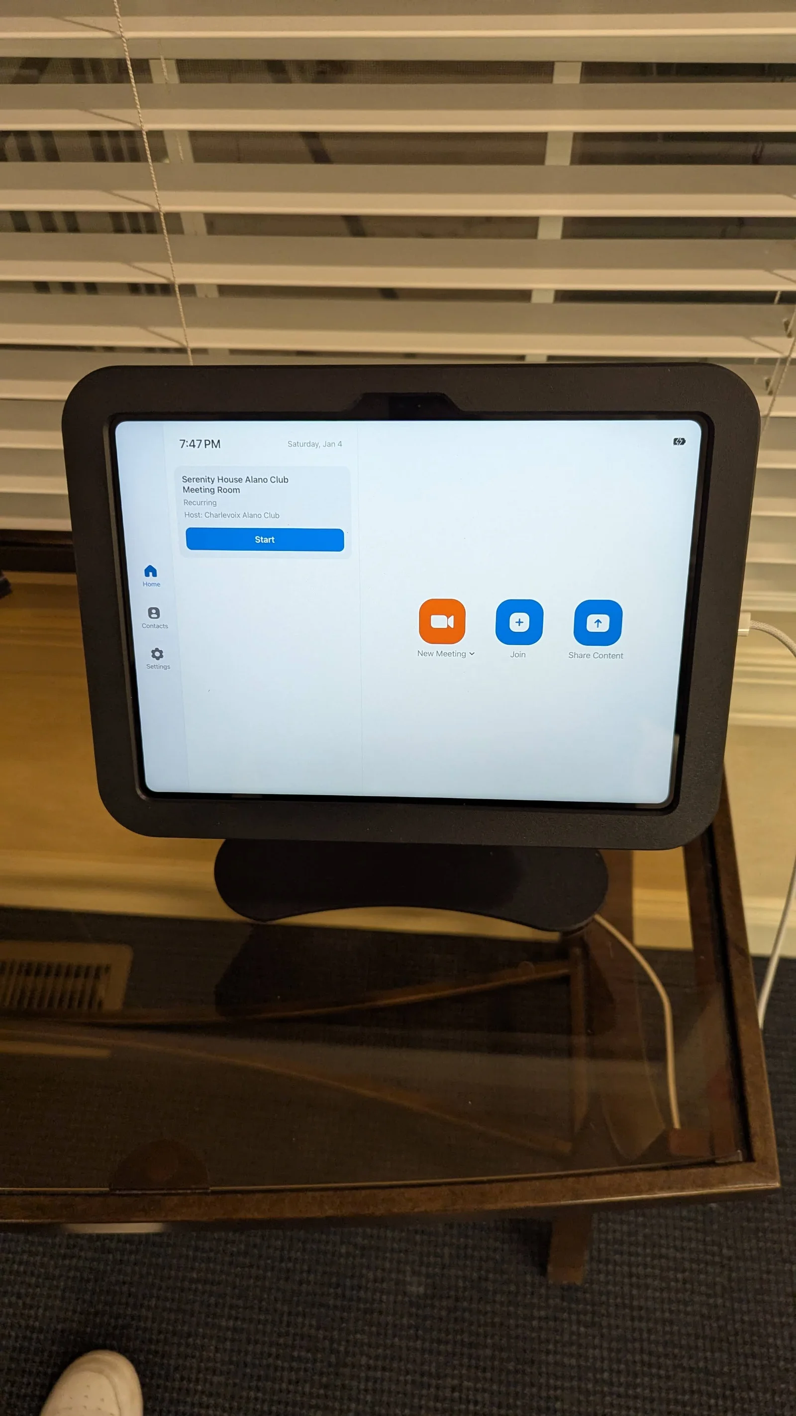 An installed Zoom Rooms touchscreen kiosk with controls to start a meeting, join, and share content